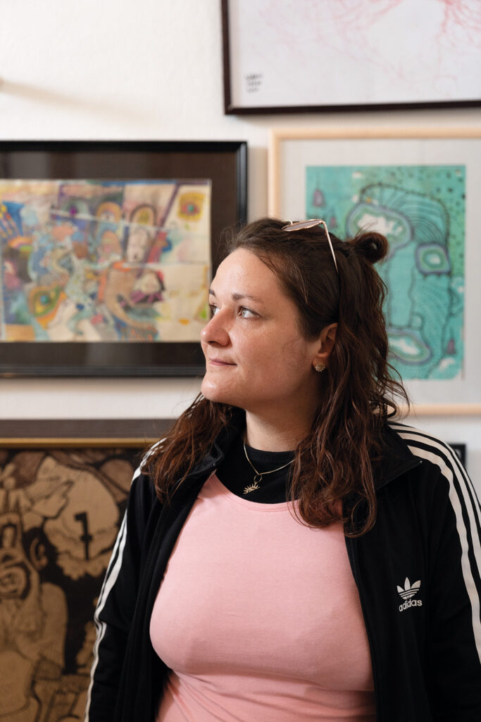 Mut: Frau steht vor gerahmten Kunstwerken und blickt zur Seite