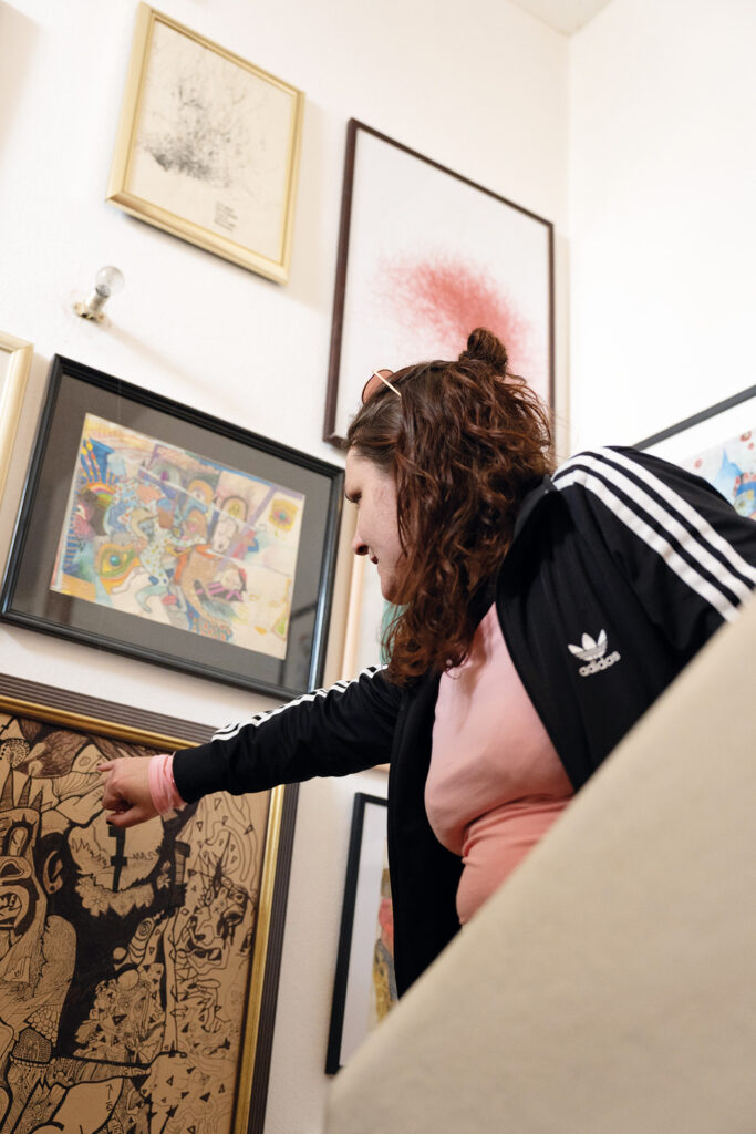 Mut: Frau zeigt auf detailreiche Zeichnung an einer Wand voller Bilder