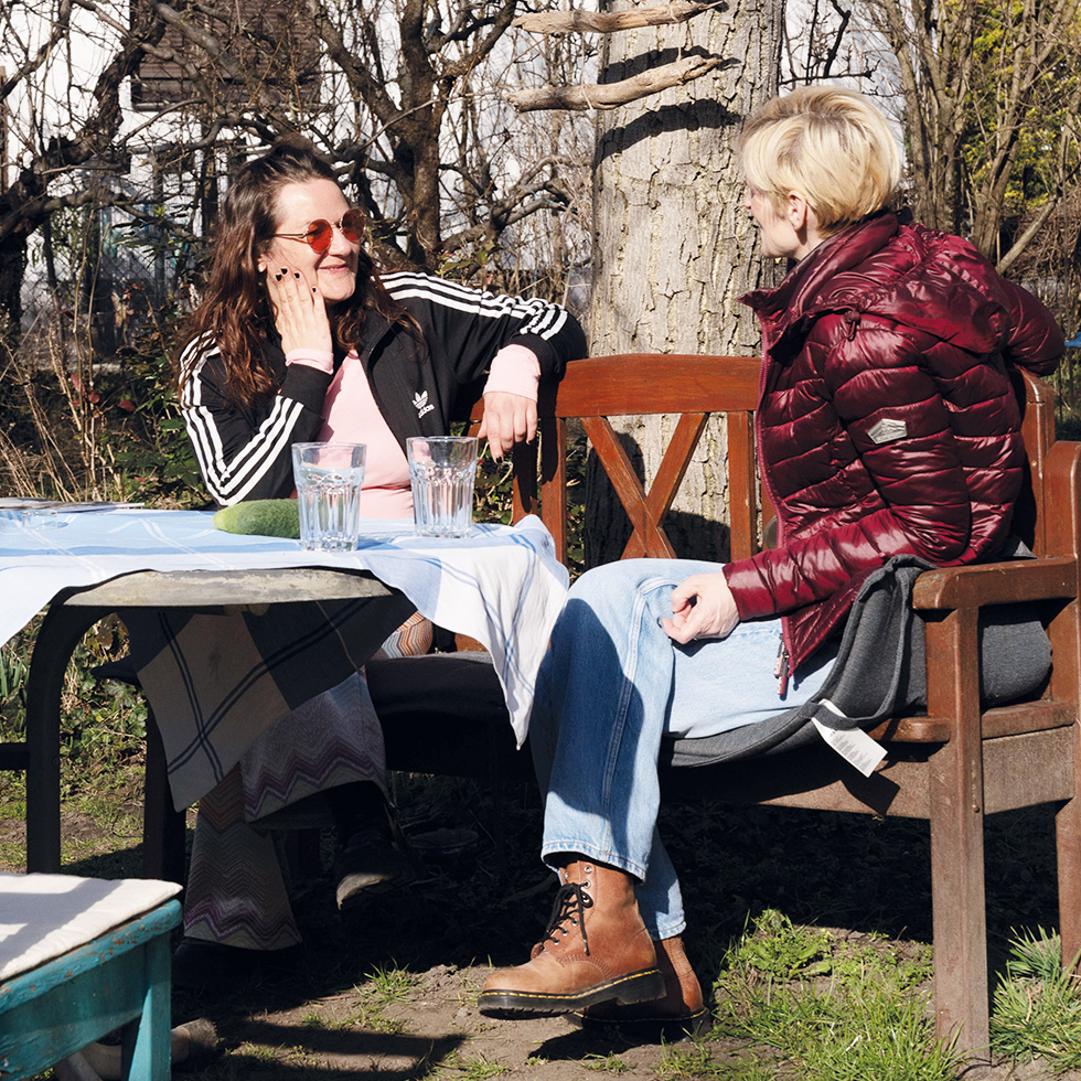 Mut: Zwei Frauen sitzen draußen am Tisch und unterhalten sich