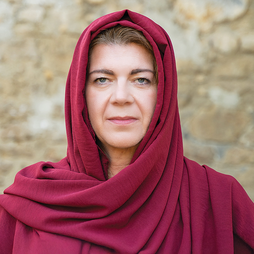 Passion: Porträt einer Frau mit rotem Tuch vor steinernem Hintergrund