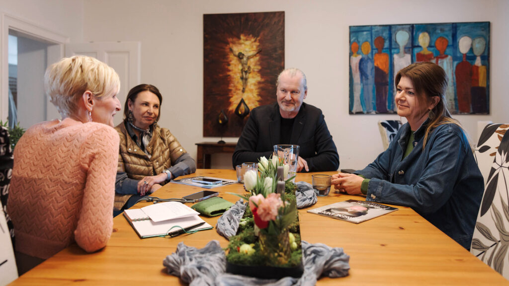 Passion: Vier Personen sitzen gemeinsam an einem Tisch im Gespräch