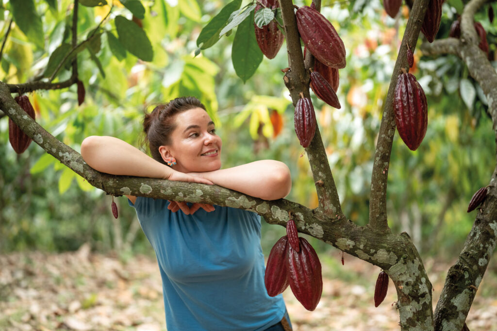 Julia Zotter lehnt an einem Kakaobaum.