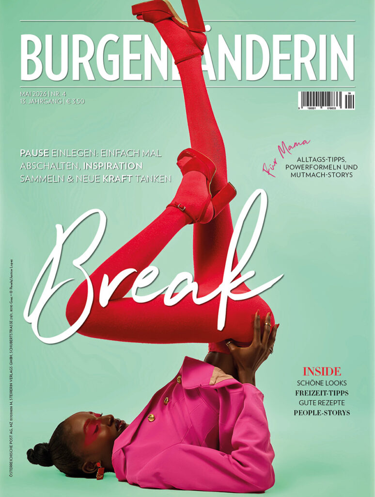 Mai-Ausgabe: Magazincover „Burgenländerin“ (Mai 2026): Frau in pinkem Outfit und roten Strumpfhosen liegt auf dem Rücken, Beine akrobatisch nach oben gestreckt; Titelthema „Break“ vor mintgrünem Hintergrund.