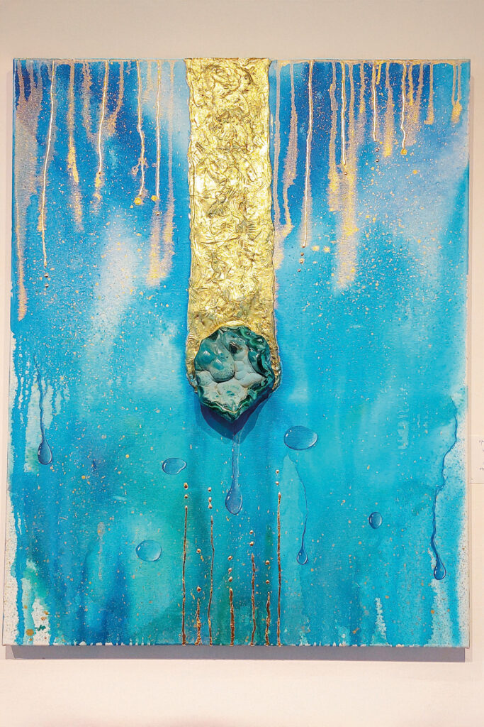 Modernes Kunstwerk von Catherine Sica mit blauem Hintergrund, goldener vertikaler Struktur und zentralem mineralartigen Element.