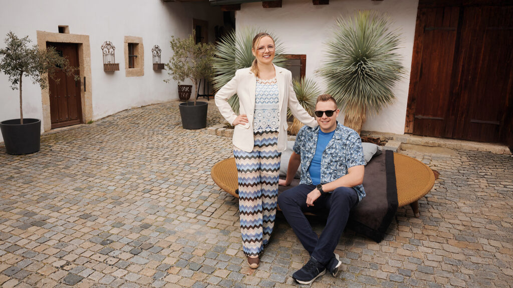 Mode: Frau und Mann posieren gemeinsam in Innenhof vor rustikalem Gebäude