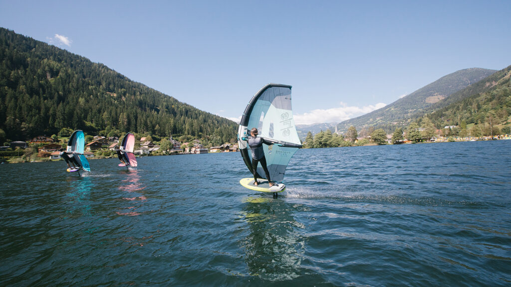 Wingfoiler gleiten auf einem See vor alpiner Kulisse – Wassersport-Event in Österreich.