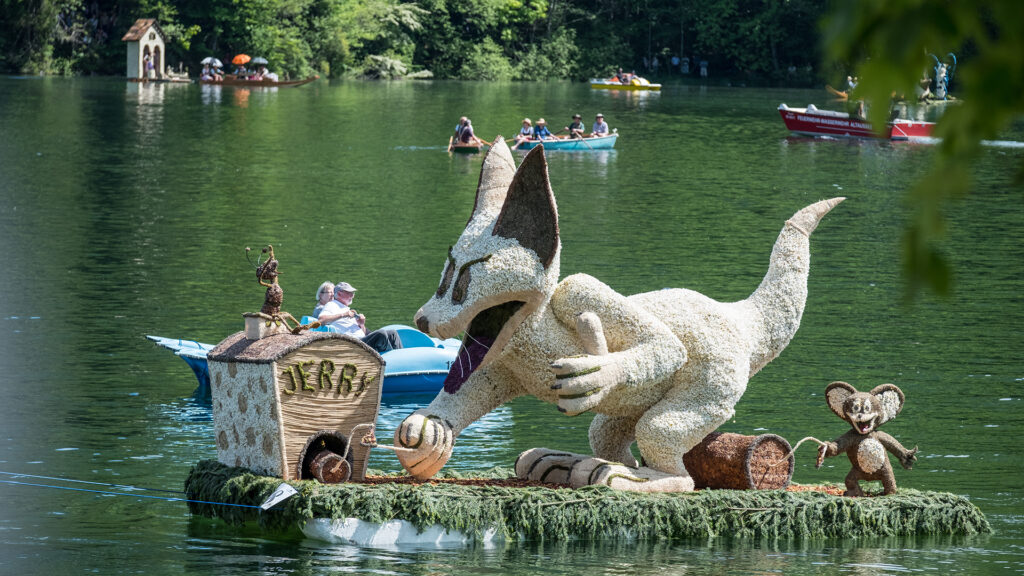 Events Österreich: Narzissenfigur auf einem geschmückten Boot beim Narzissenfest auf dem See – traditionelles Event in Österreich.