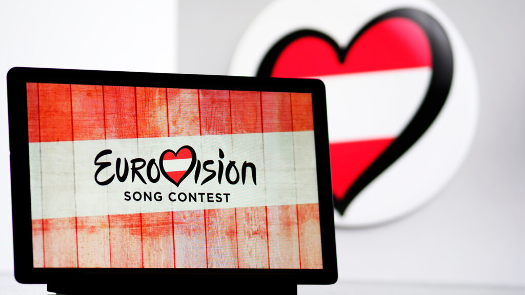 Events Österreich: Bildschirm mit Logo des Eurovision Song Contest vor österreichischer Flagge – internationales Musikevent in Österreich.