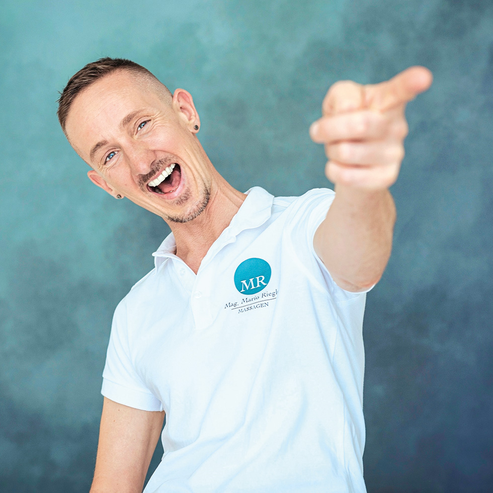 Mann in weißem Poloshirt mit dynamischer Pose und humorvollem Ausdruck vor blauem Hintergrund.