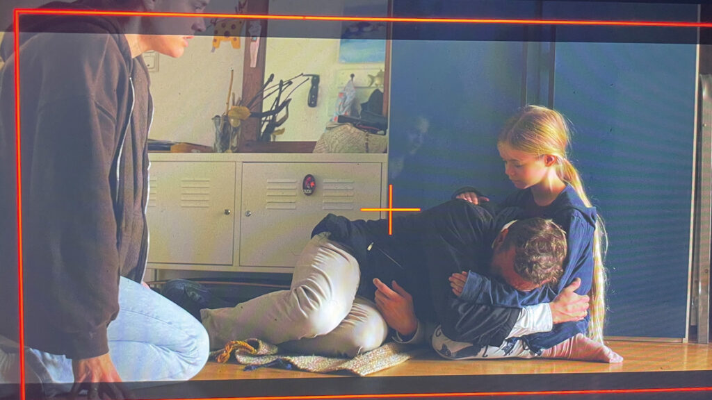 Filmszene hinter der Kamera: Vater umarmt seine Tochter am Boden, während eine weitere Person zusieht – Making-of von „Bester Papa, manchmal“.
