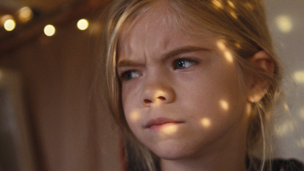 Ernst blickendes Mädchen mit Lichtreflexen im Gesicht – Szene aus dem Kurzfilm „Bester Papa, manchmal“.