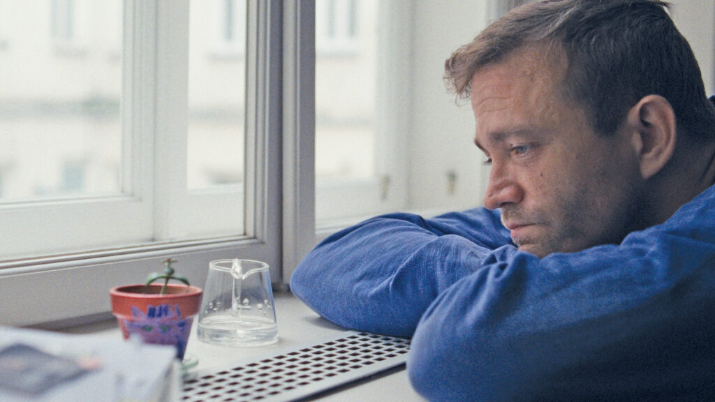 Nachdenklicher Mann sitzt am Fenster und blickt aus dem Fenster – Szene aus „Bester Papa, manchmal“.