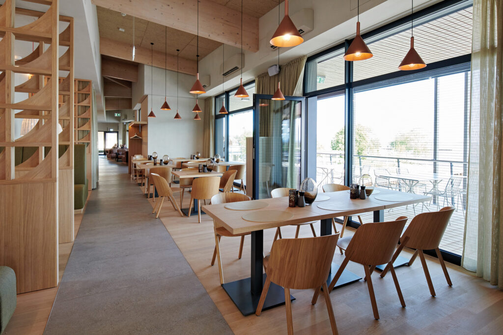 Modernes Restaurantdesign mit warmen Holzelementen und großzügigem Blick auf den Neusiedler See.