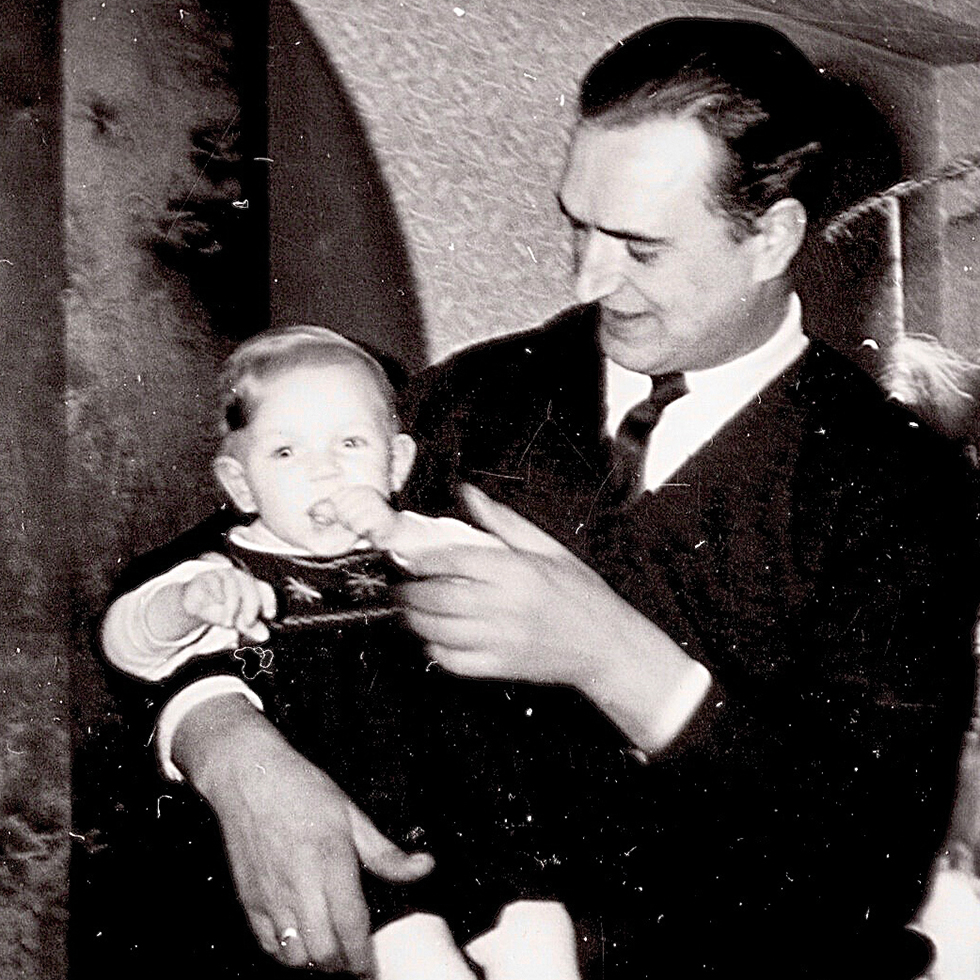 Schwarz-Weiß-Aufnahme eines Vaters mit Baby auf dem Arm als emotionales Erinnerungsbild zum Vatertag.