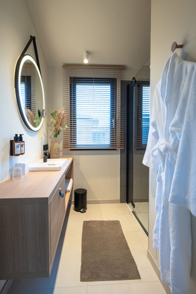 Helles Badezimmer mit minimalistischer Ausstattung und Wellness-Flair im neuen Strand-Resort.