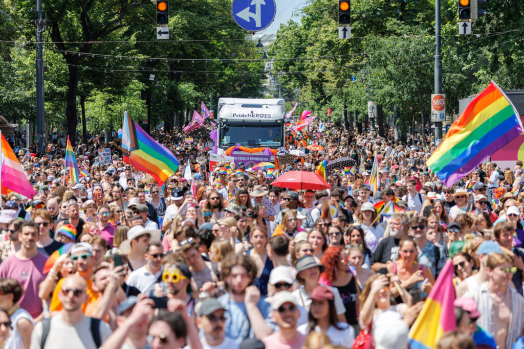Was ist los: Regenbogenparade mit zahlreichen Teilnehmern, Pride-Flaggen und sommerlicher Festivalatmosphäre in der Stadt.