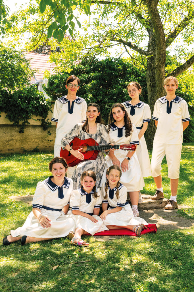 Kunst: Junge Darstellerinnen und Darsteller posieren in historischen Kostümen mit Gitarre für eine Theater- oder Musicalproduktion.