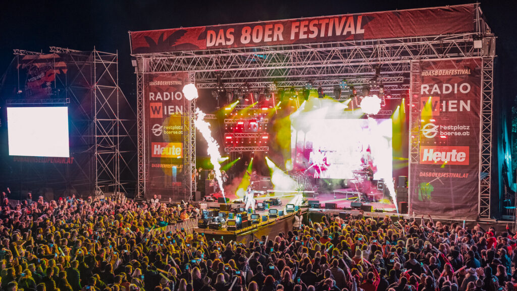 Events: Festivalpublikum erlebt eine Live-Show mit Licht-, Pyro- und Bühneneffekten bei einem Abendkonzert.