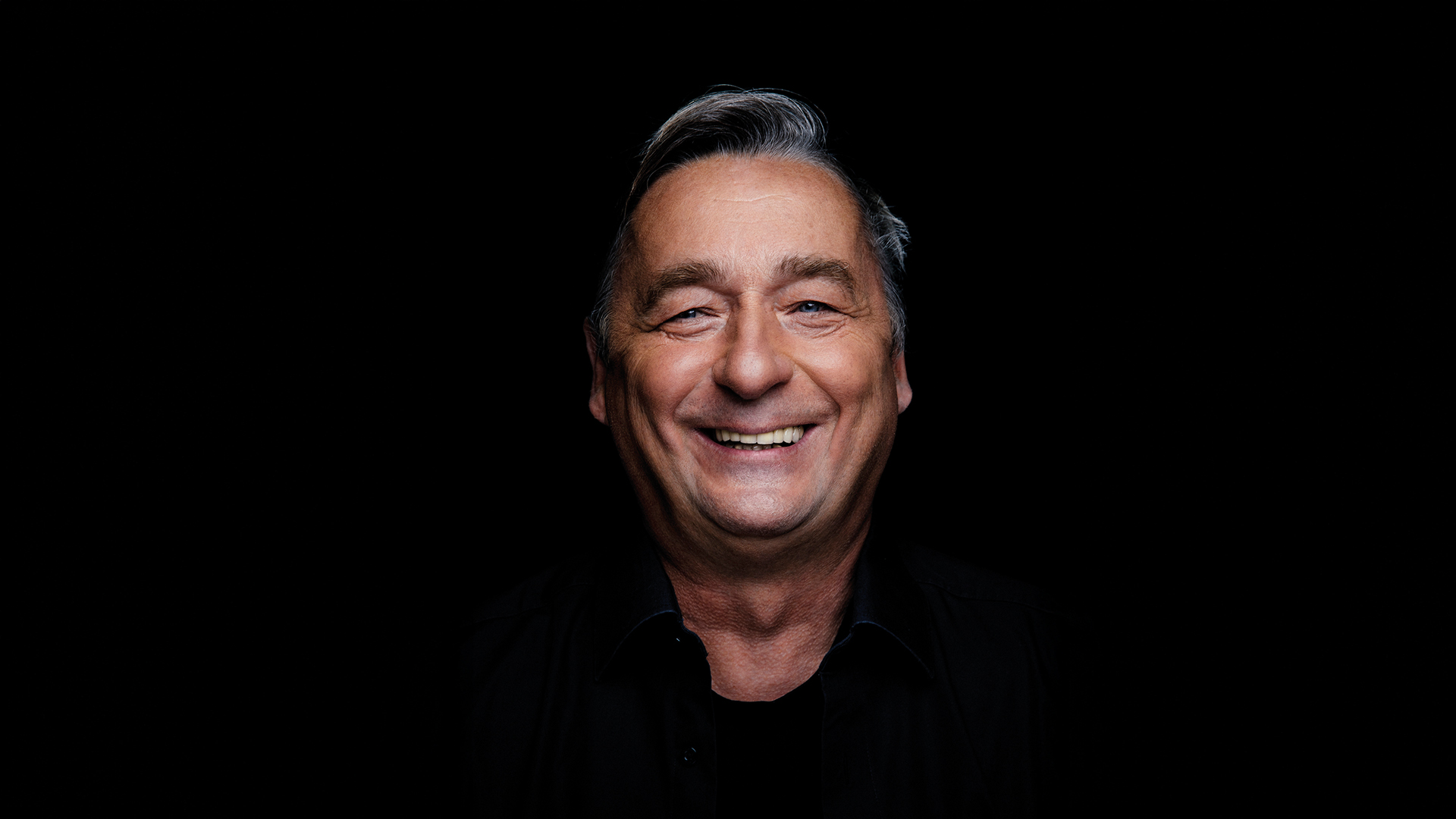 Porträt des Kabarettisten Andreas Vitásek vor schwarzem Hintergrund beim Kultursommer Güssing.