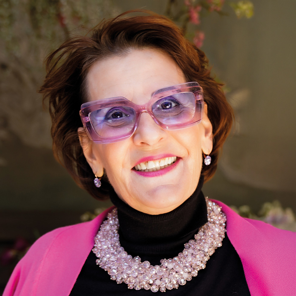 Porträt einer Frau mit auffälliger rosa Brille und Statement-Schmuck – eine der Top 100 Frauen des Jahres.