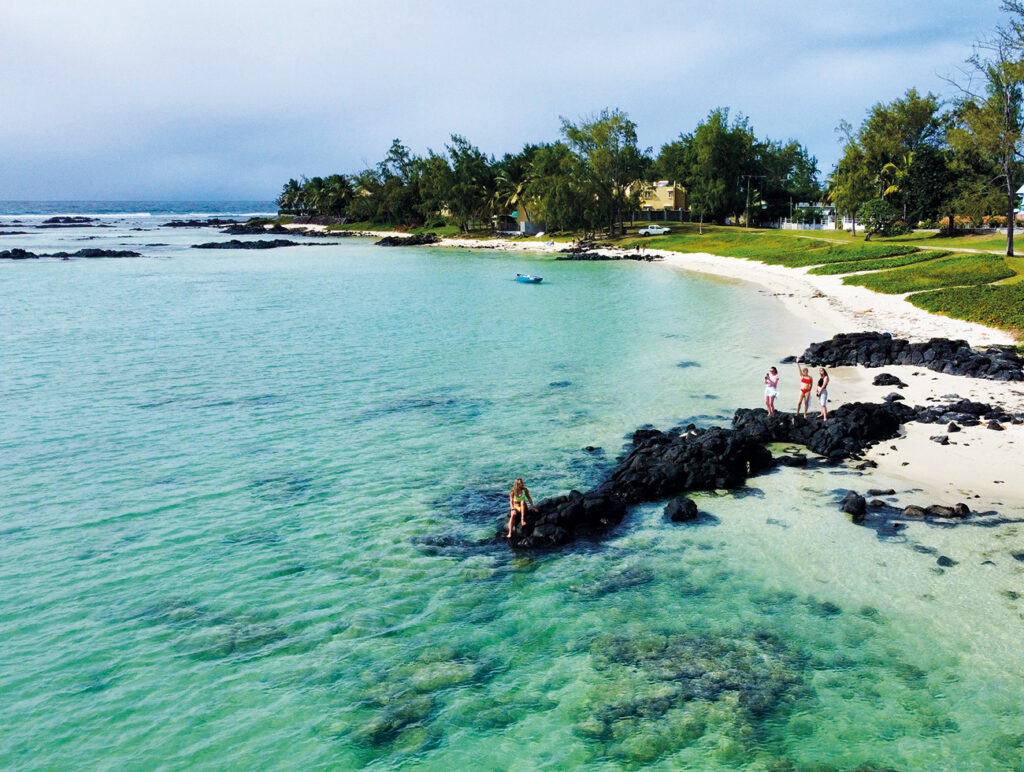 Luftaufnahme einer idyllischen Bucht mit schwarzem Lavagestein und kristallklarem Wasser auf Mauritius.