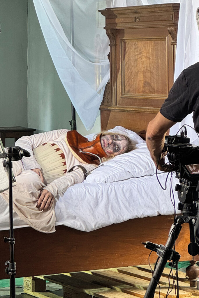 Selina Heindl bei Dreharbeiten in historischem Kostüm auf einem Bett vor der Filmkamera.