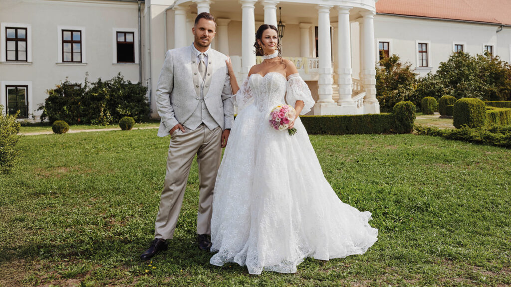 Hochzeitsshooting mit Braut und Bräutigam in eleganter Hochzeitsmode vor historischer Schlosskulisse