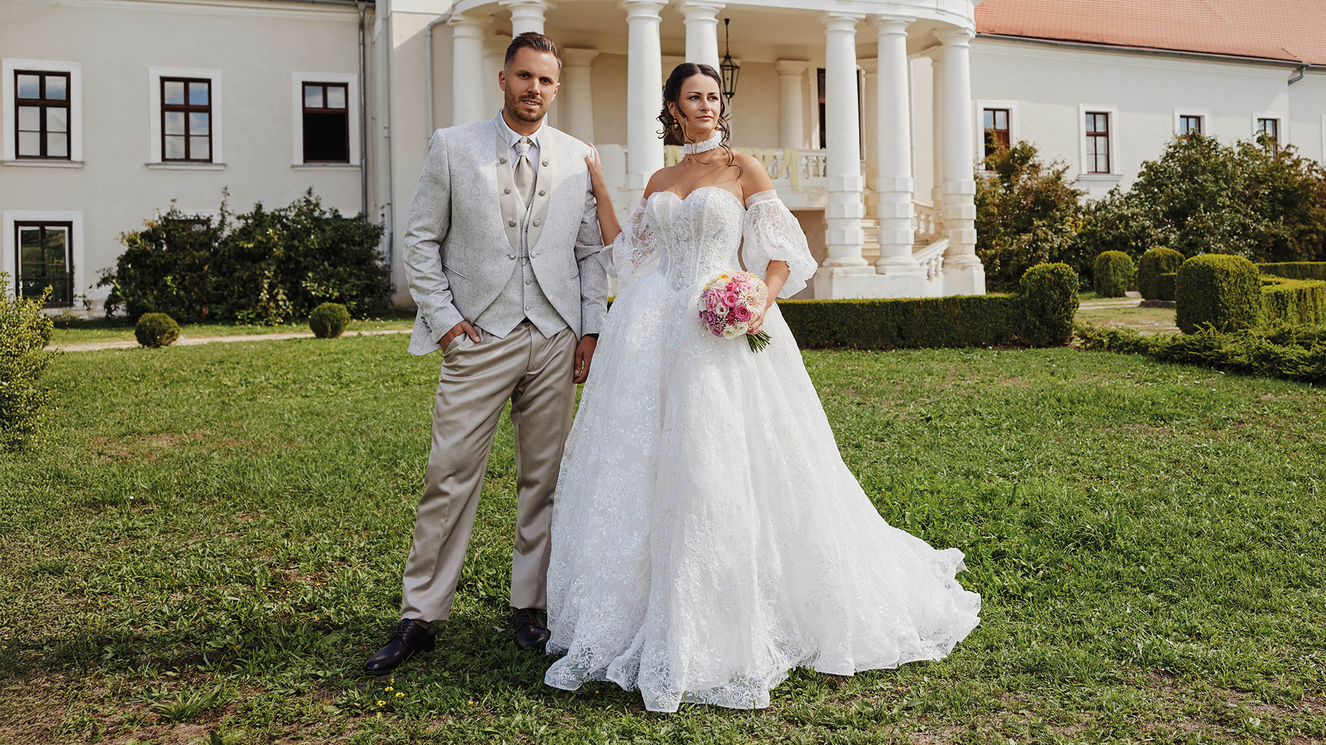 Hochzeitsshooting mit Braut und Bräutigam in eleganter Hochzeitsmode vor historischer Schlosskulisse