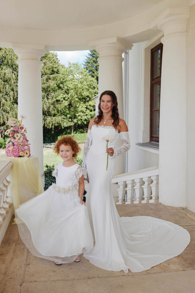 Hochzeitsshooting mit Braut und Blumenmädchen in weißen Kleidern vor romantischer Schlosskulisse