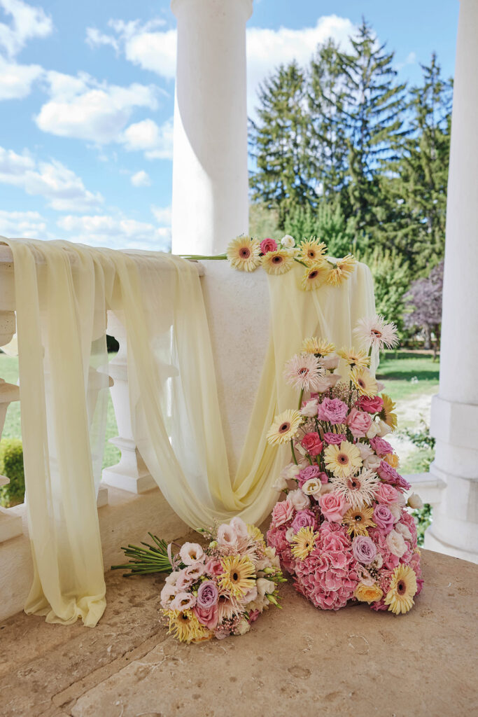 Hochzeitsshooting mit romantischer Blumendekoration in Rosa und Gelb vor sommerlicher Schlosskulisse