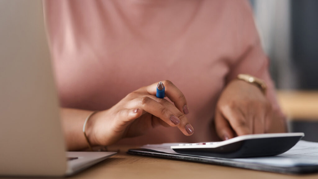Female Finance: Frau erstellt mit Laptop, Taschenrechner und Unterlagen einen persönlichen Finanz- und Budgetplan.