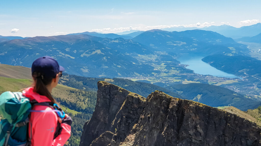 Alleinreisen in Kärnten: Wanderin genießt den Ausblick auf den Millstätter See und die Berglandschaft.