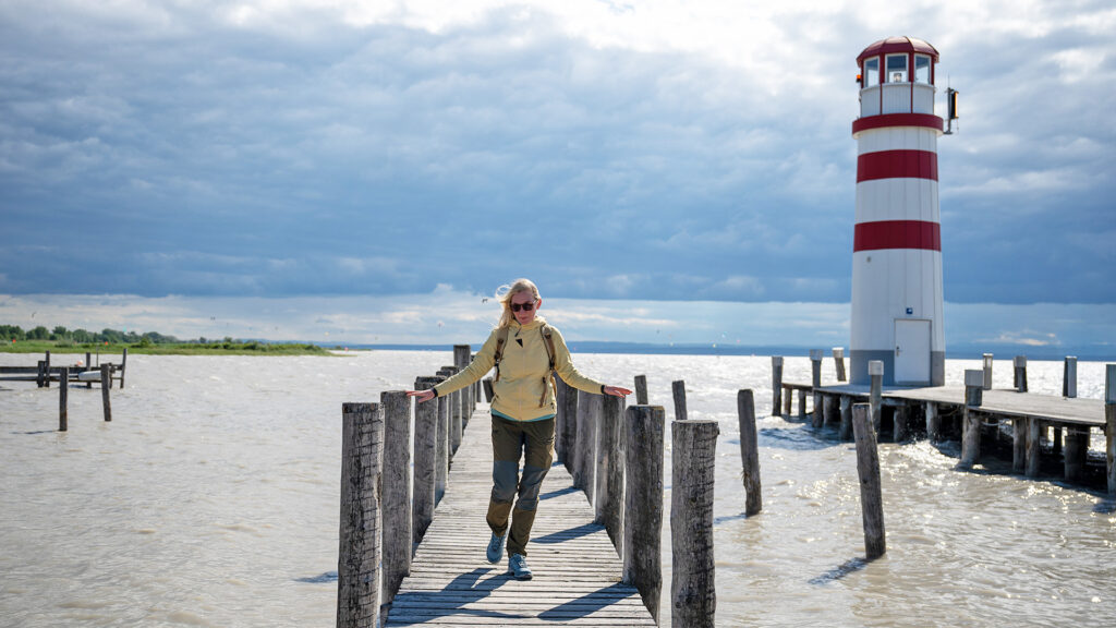 Alleinreisen am Neusiedler See: Frau spaziert auf einem Steg neben dem Leuchtturm.