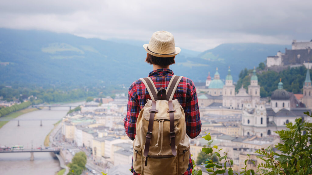 Alleinreisen in Salzburg: Reisende mit Rucksack blickt über die Salzburger Altstadt.