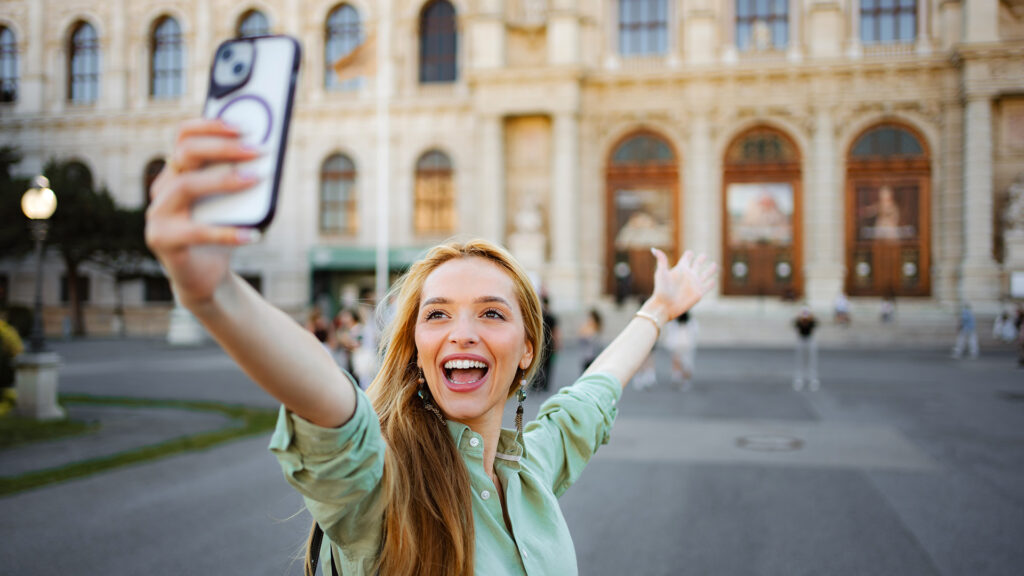 Alleinreisen in Wien: Frau macht ein Selfie vor einem historischen Gebäude.